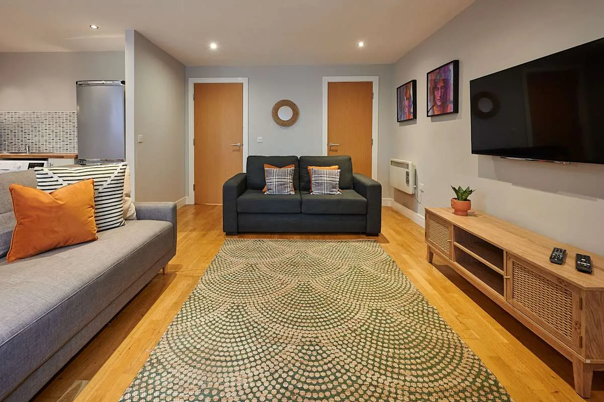 Una sala de estar con asientos, un televisor y una alfombra estampada.