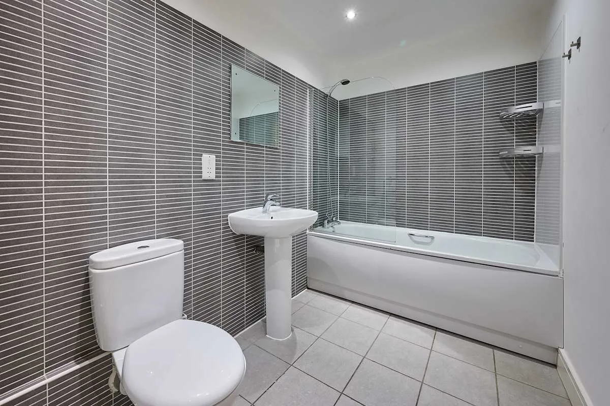 Un baño con azulejos, bañera, lavabo e inodoro.