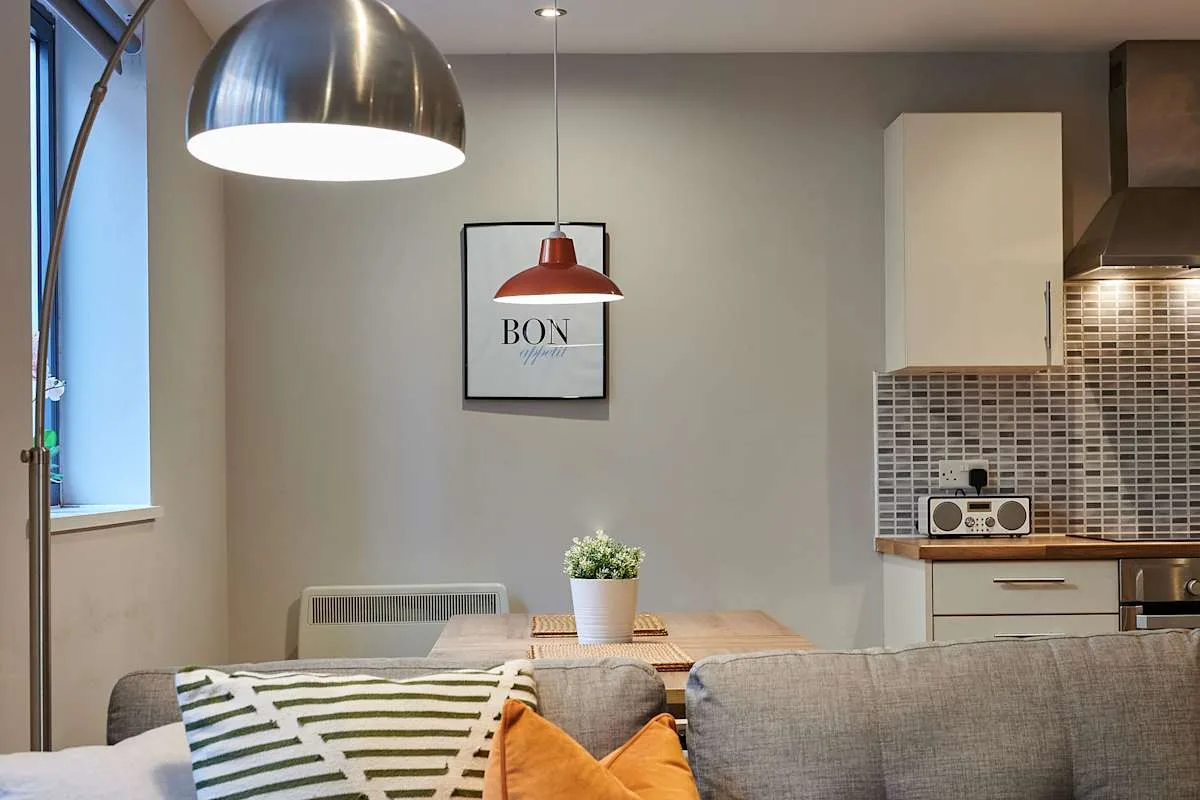 Una zona de comedor y estar con una mesa de madera, asientos y una cocina compacta.