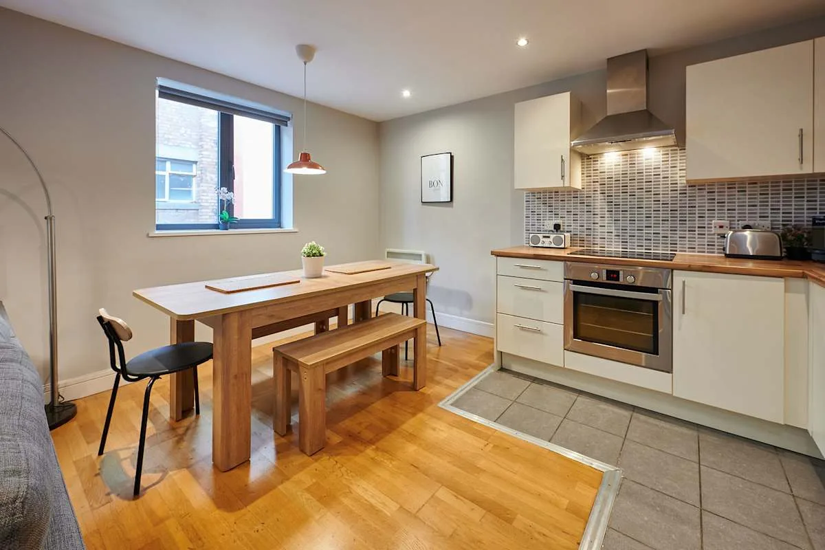 Comedor con una mesa y un banco de madera junto a una cocina abierta.