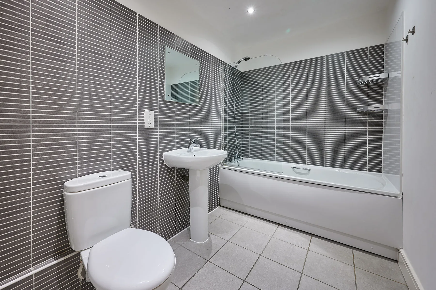 Un baño alicatado con bañera, lavabo e inodoro.