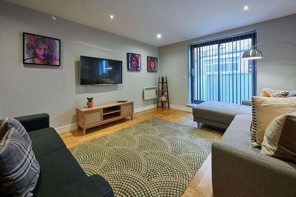 Sala de estar con asientos, un televisor y una alfombra grande estampada.