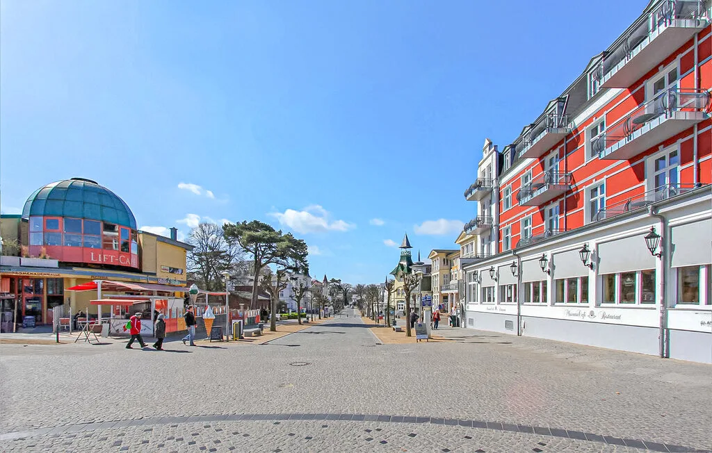 Una calle peatonal flanqueada por tiendas y edificios bajo un cielo azul despejado.