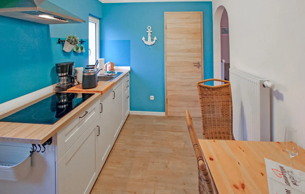 Una cocina compacta con armarios blancos, una placa de cocina y una mesa de madera.