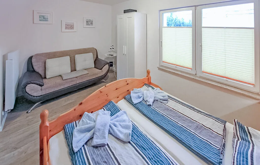 Un dormitorio luminoso con dos camas, un sofá y ventanas grandes.