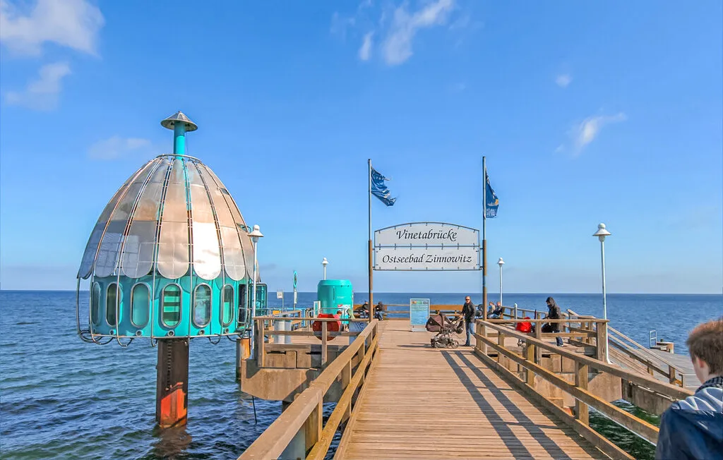Un muelle de madera se adentra en el agua bajo un cielo azul despejado.