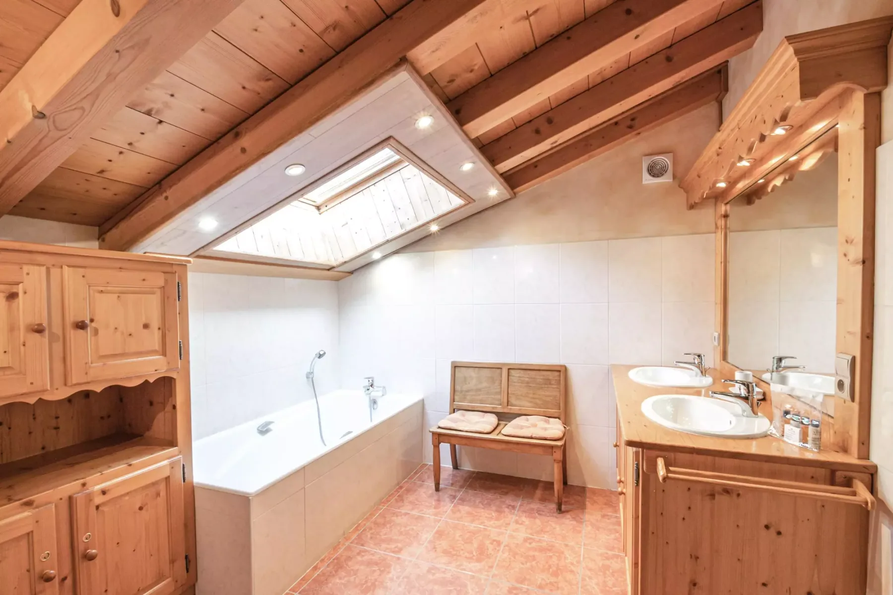 A bathroom with a bathtub, double sinks, and wooden cabinetry.