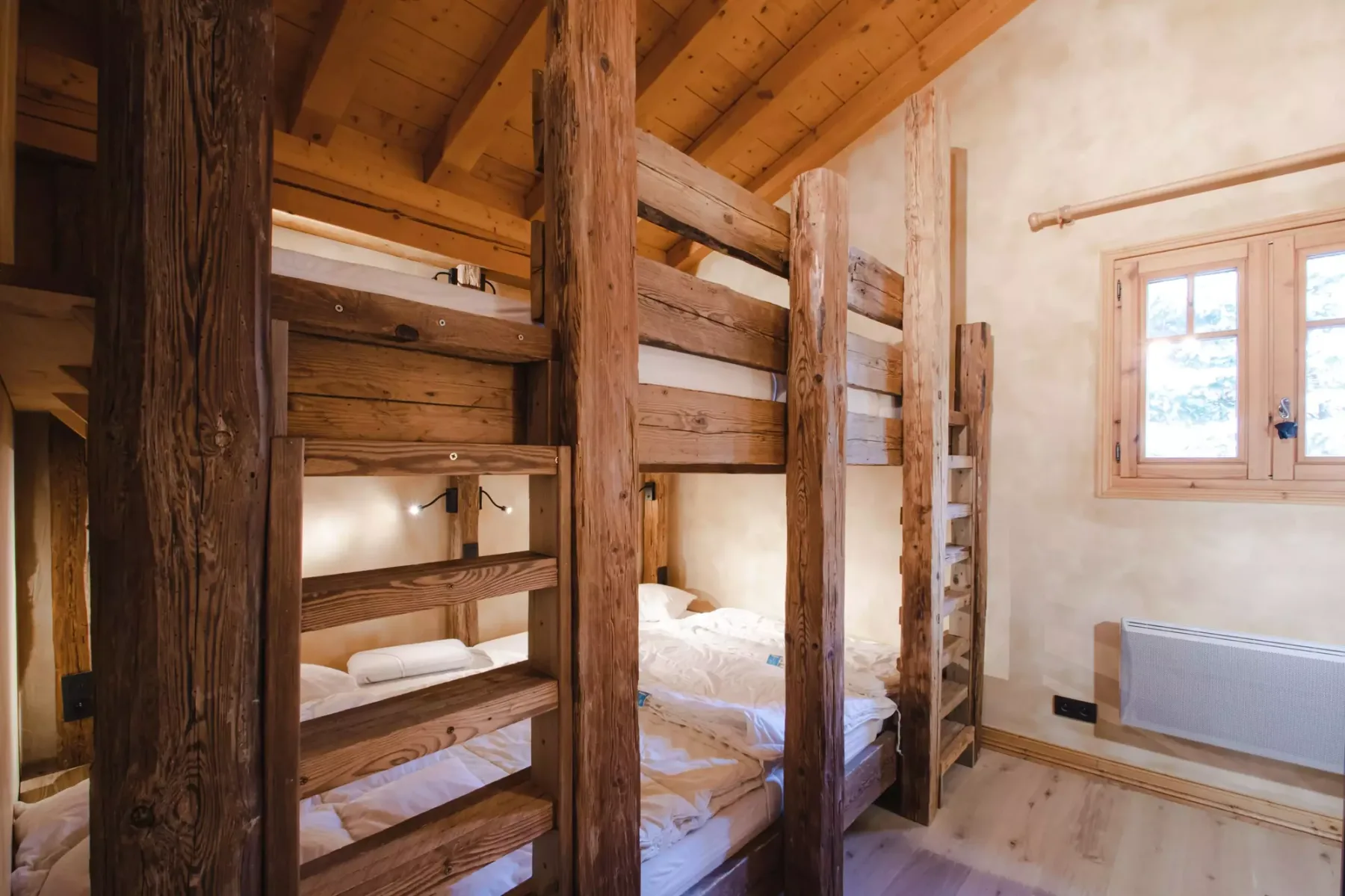 A bedroom with wooden bunk beds and a window.