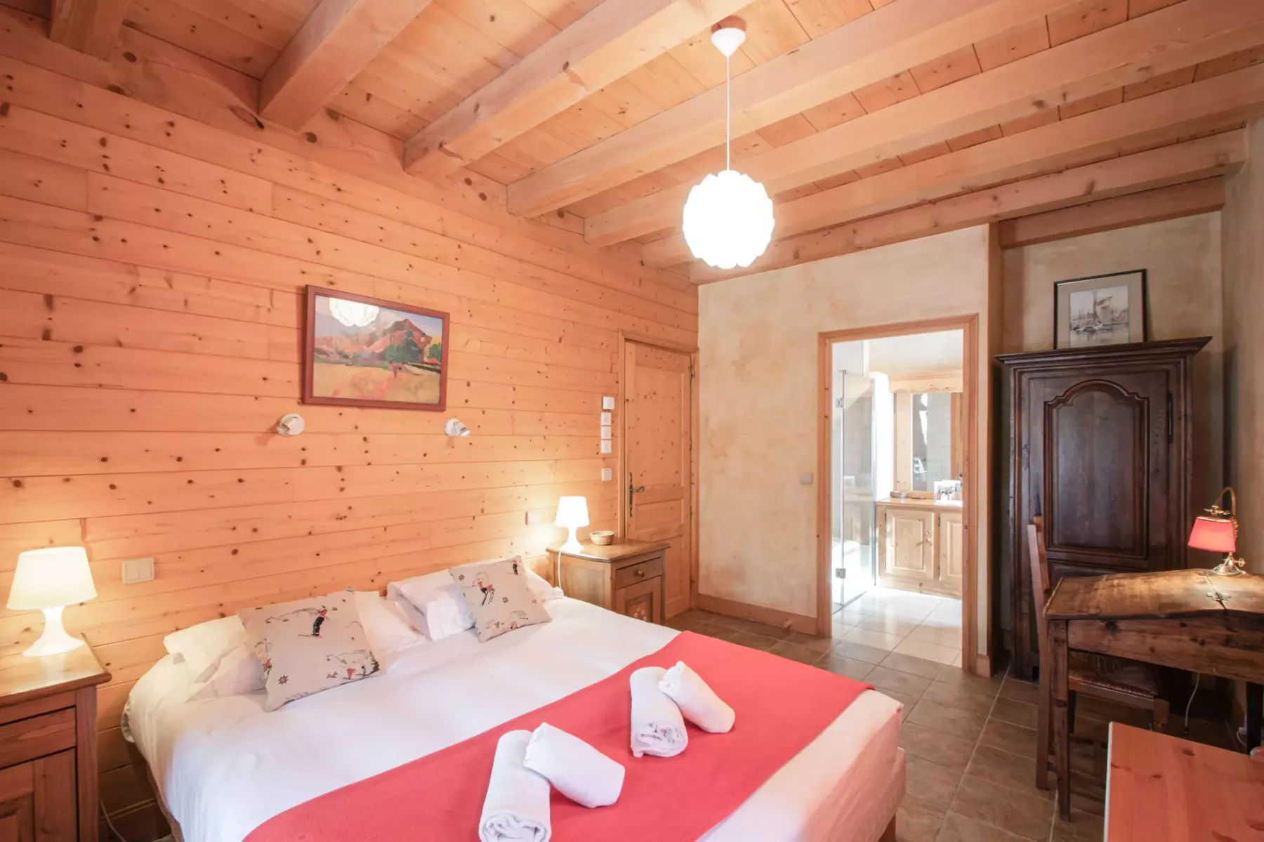 A bedroom with a bed, wood-paneled walls, and exposed ceiling beams.