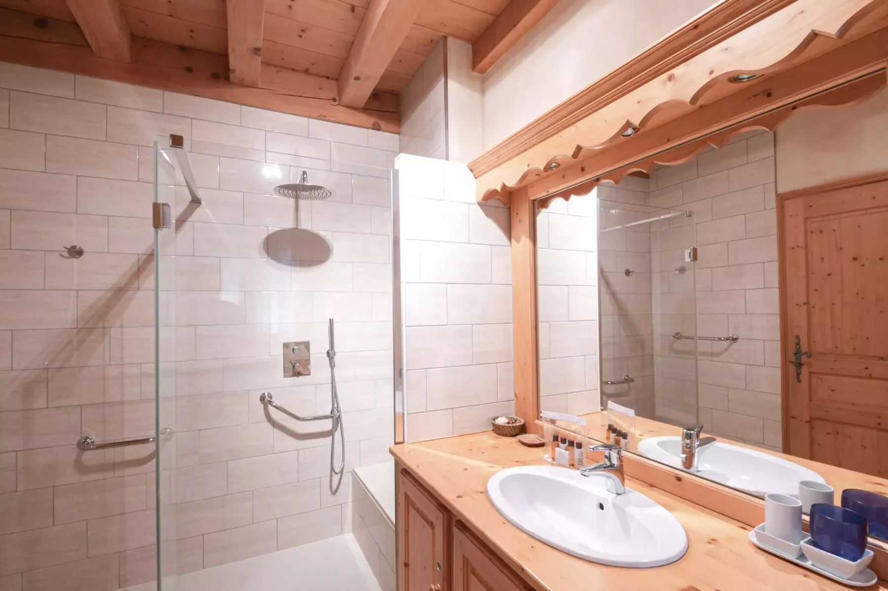 A tiled bathroom with a shower, bathtub, and sink beneath a wooden ceiling.