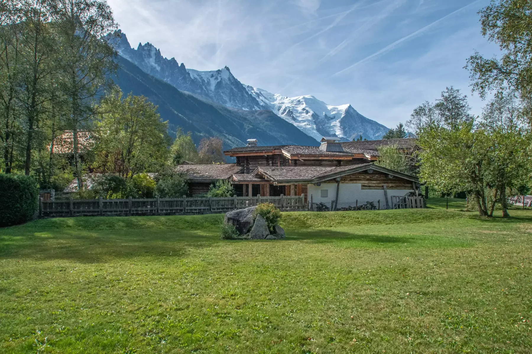 A grassy lawn overlooks low buildings and a snow-capped mountain range.