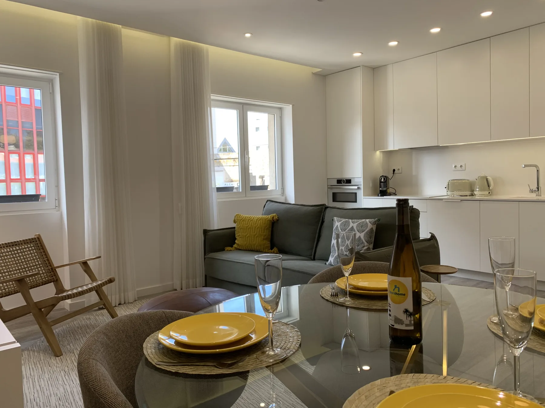 Una moderna zona de estar y comedor con sofá, mesa y cocina compacta.