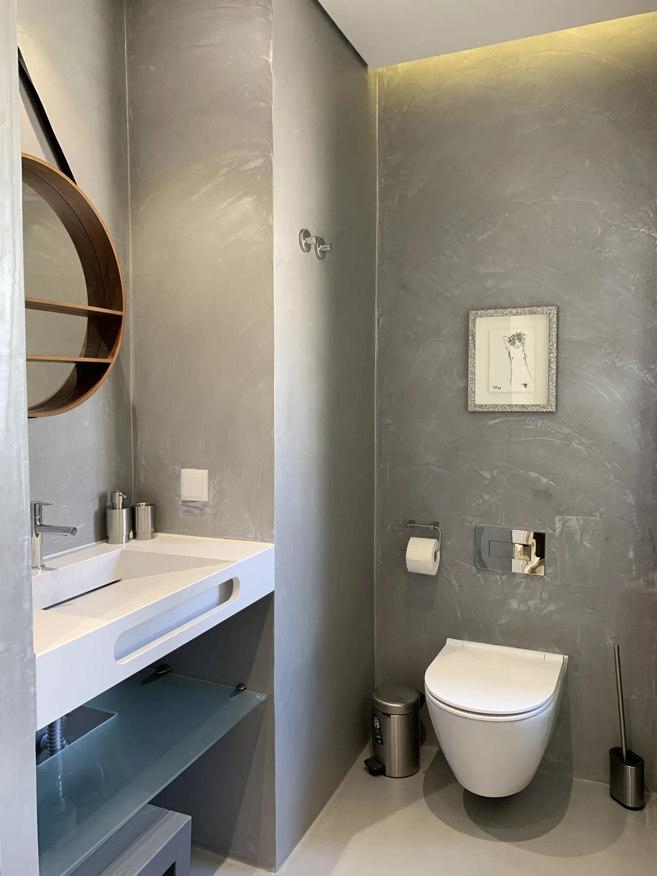 Un baño moderno con un inodoro suspendido y un lavabo.