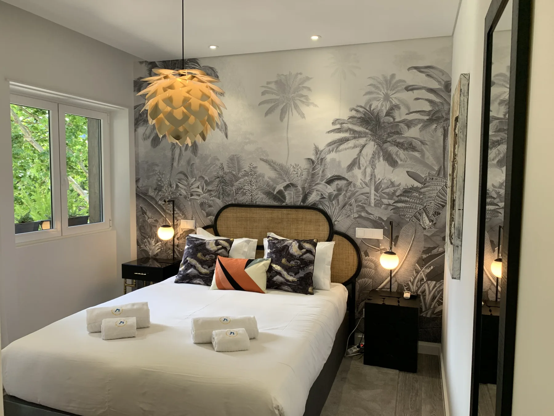 Un dormitorio con una cama bien tendida y un mural de palmeras.