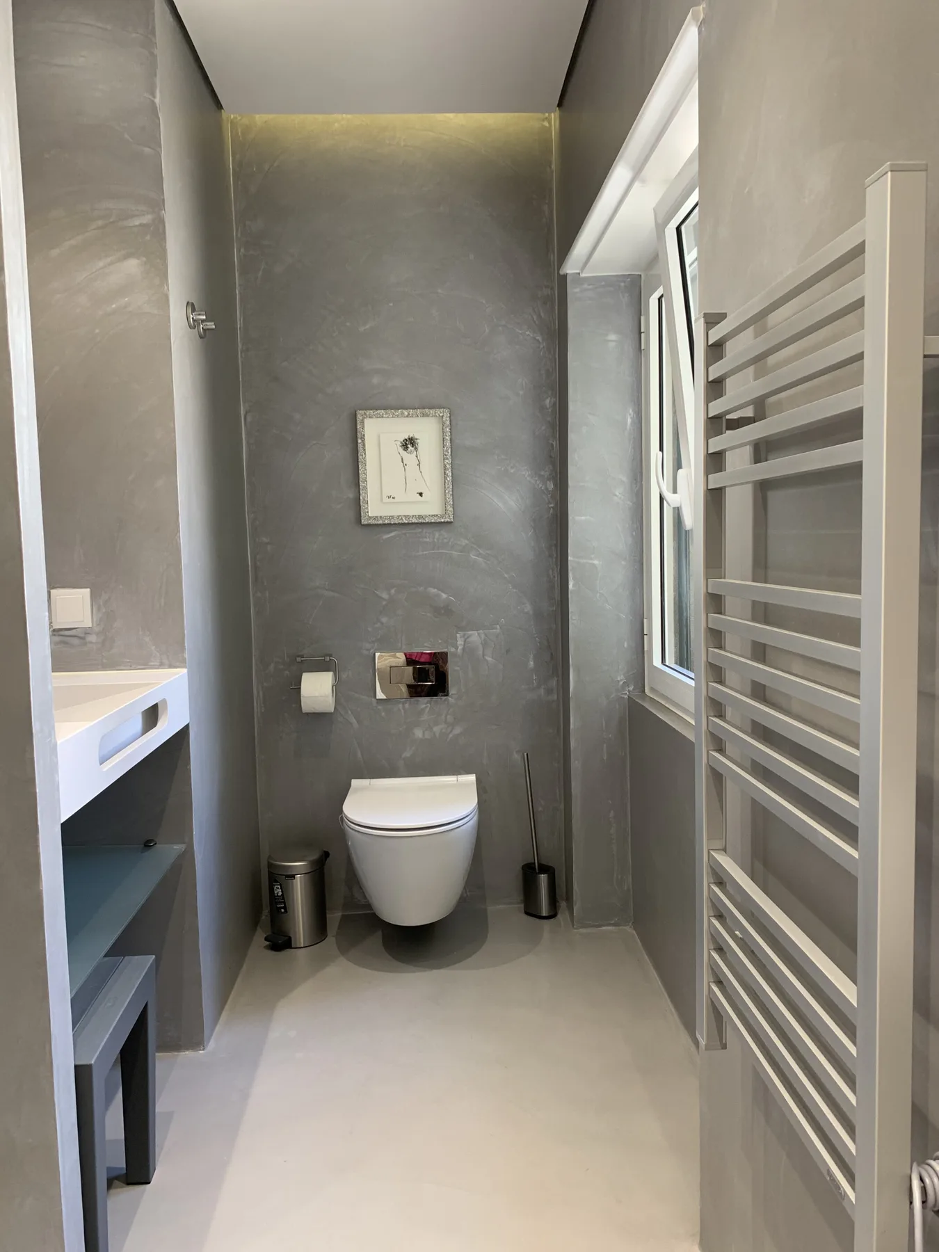Un baño moderno con un inodoro suspendido y un toallero alto.