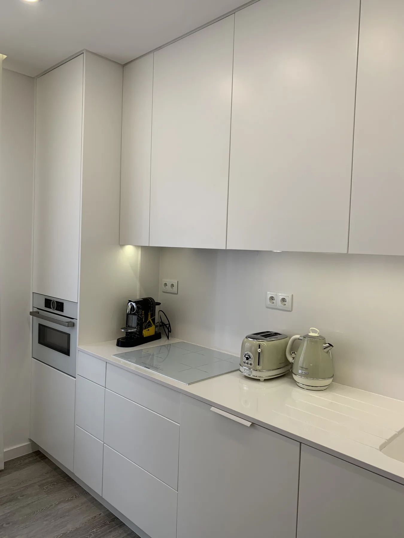 Una cocina moderna con gabinetes blancos, una encimera y pequeños electrodomésticos.