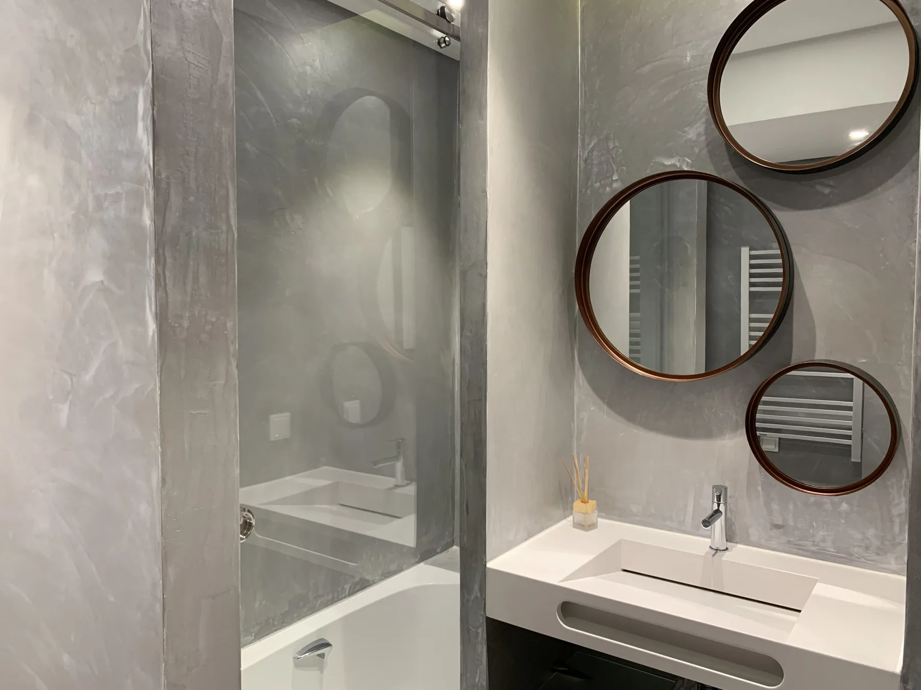 Un baño moderno con bañera, lavabo y espejos redondos en la pared.