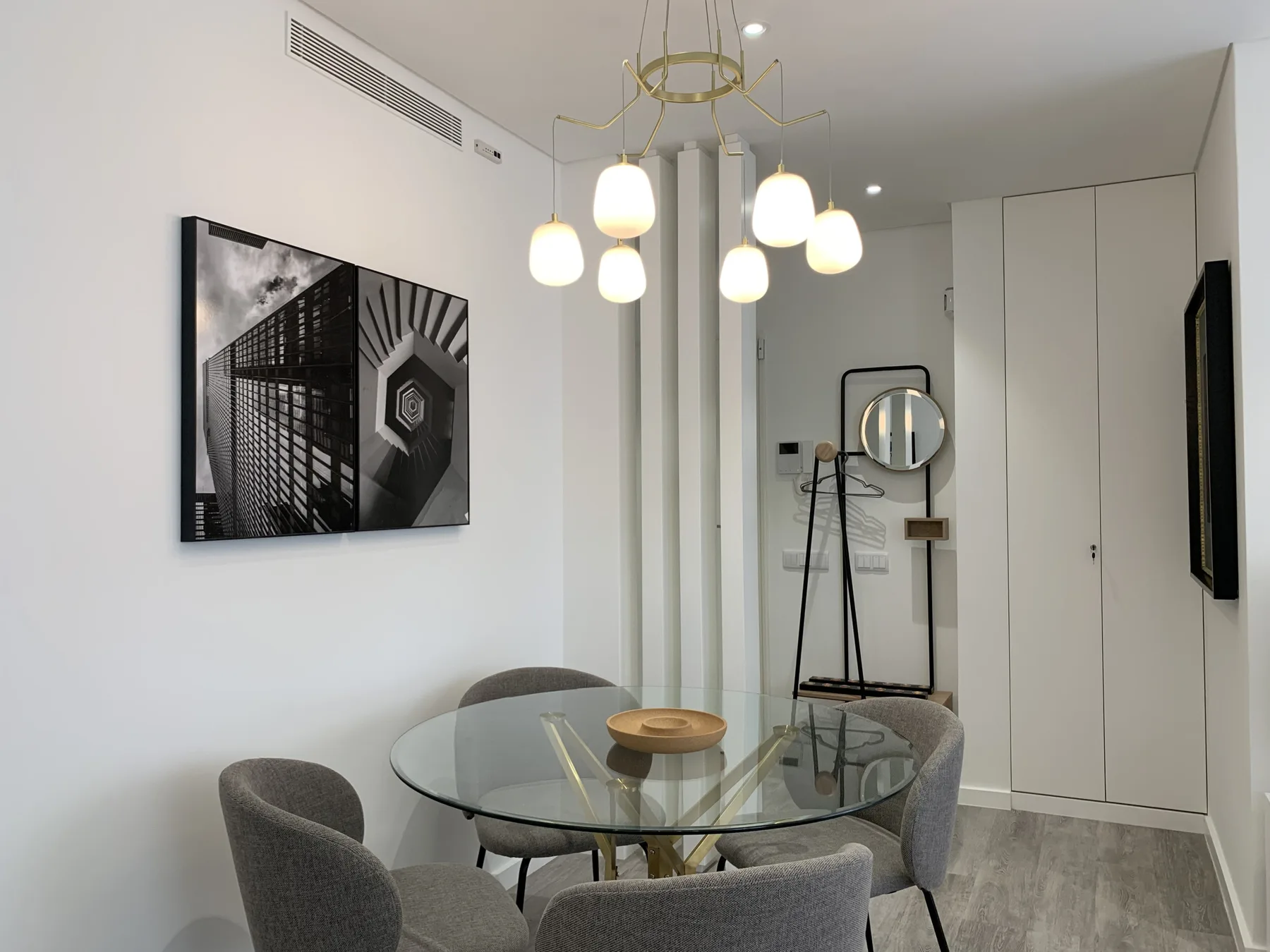 Comedor con una mesa de vidrio, asientos y lámparas colgantes.