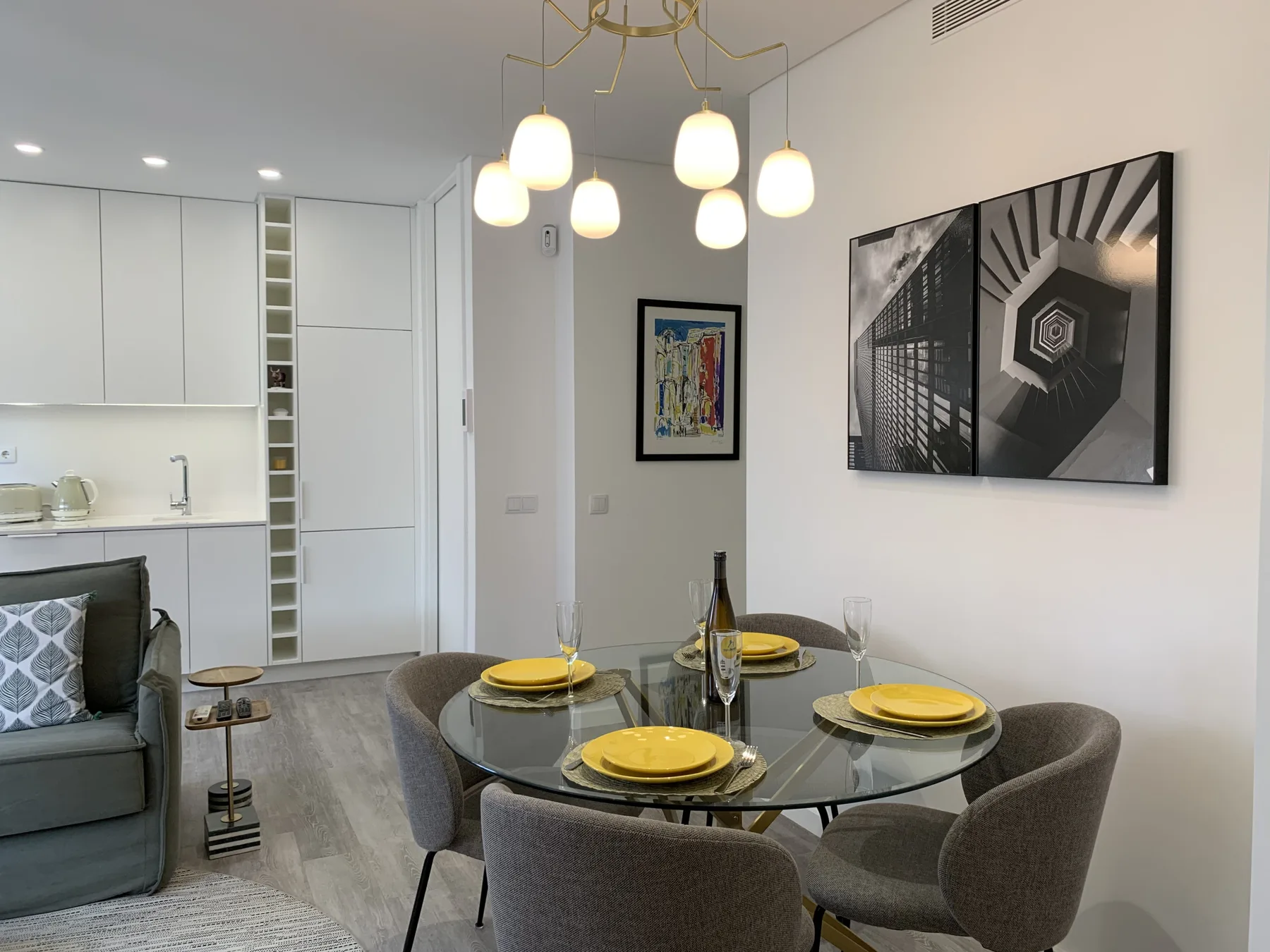Una zona moderna de comedor y sala de estar con mesa de vidrio y asientos grises.
