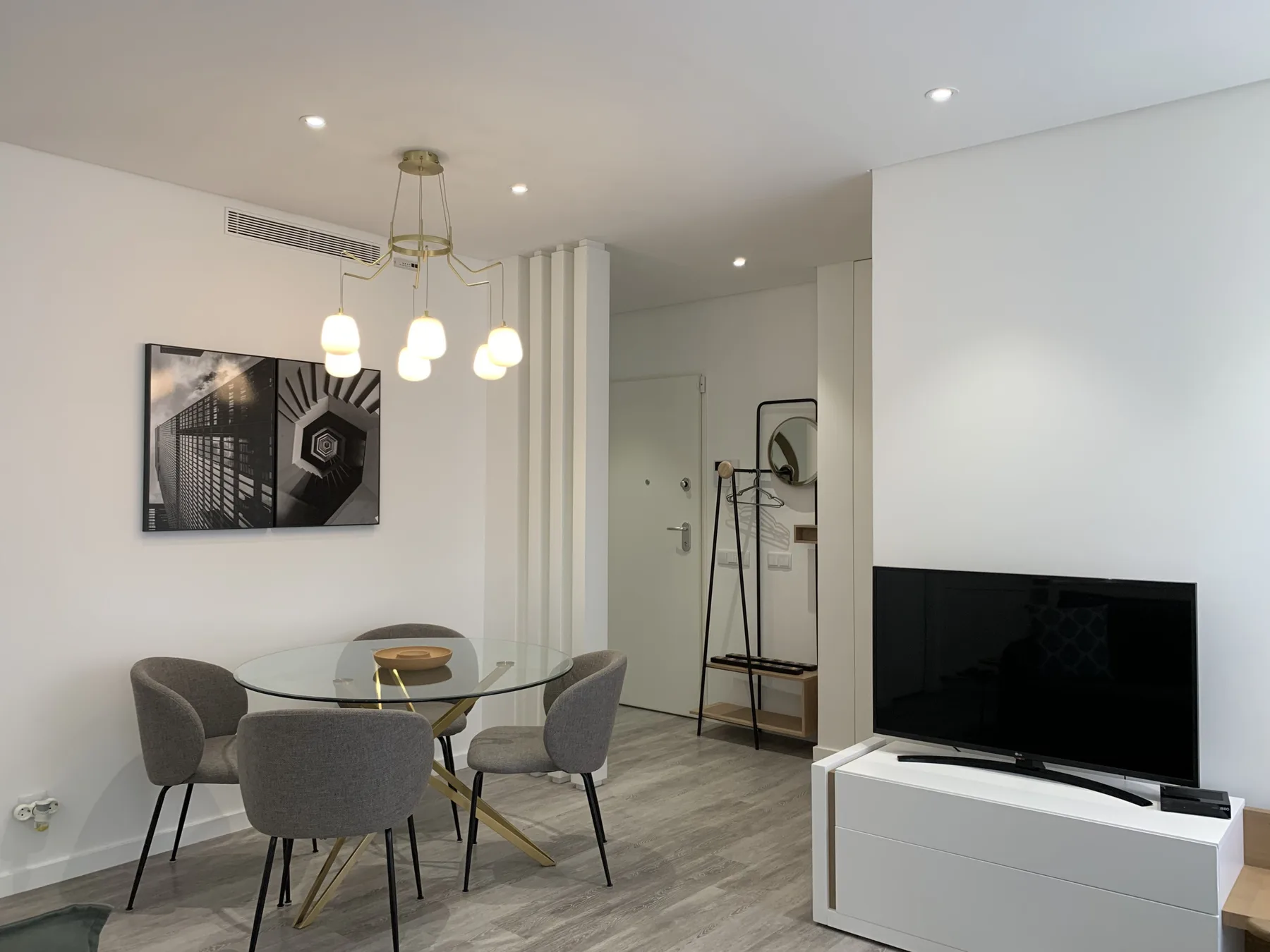 Una sala de estar y comedor moderna con una mesa de vidrio, asientos y un televisor.