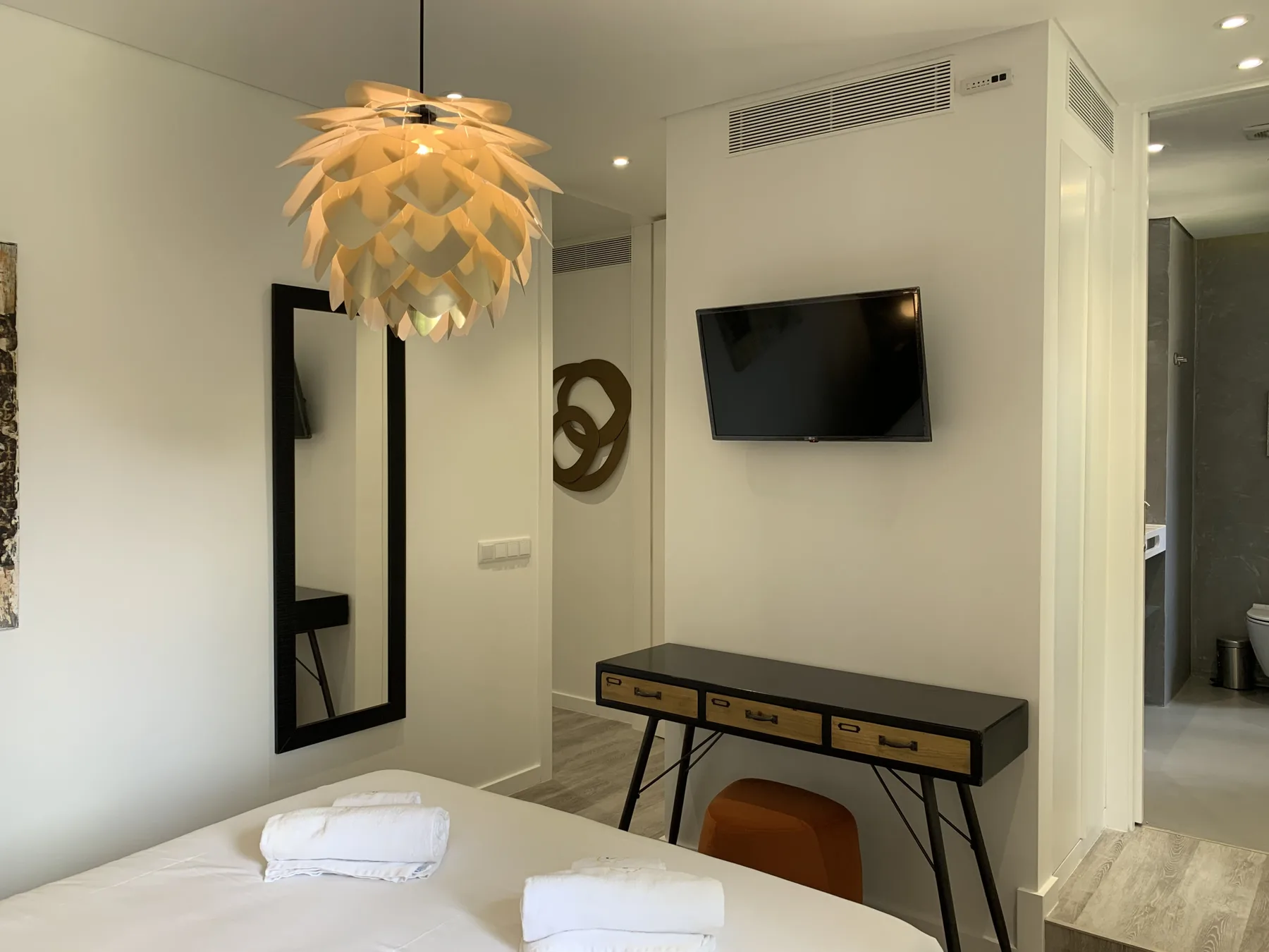 Un dormitorio con un televisor montado en la pared sobre un escritorio.