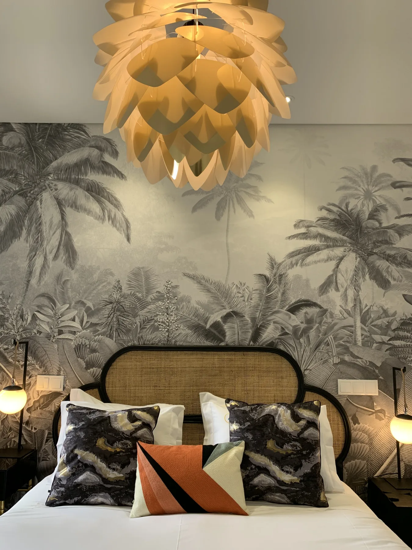 Un dormitorio con una cama bien tendida y papel tapiz con palmeras.