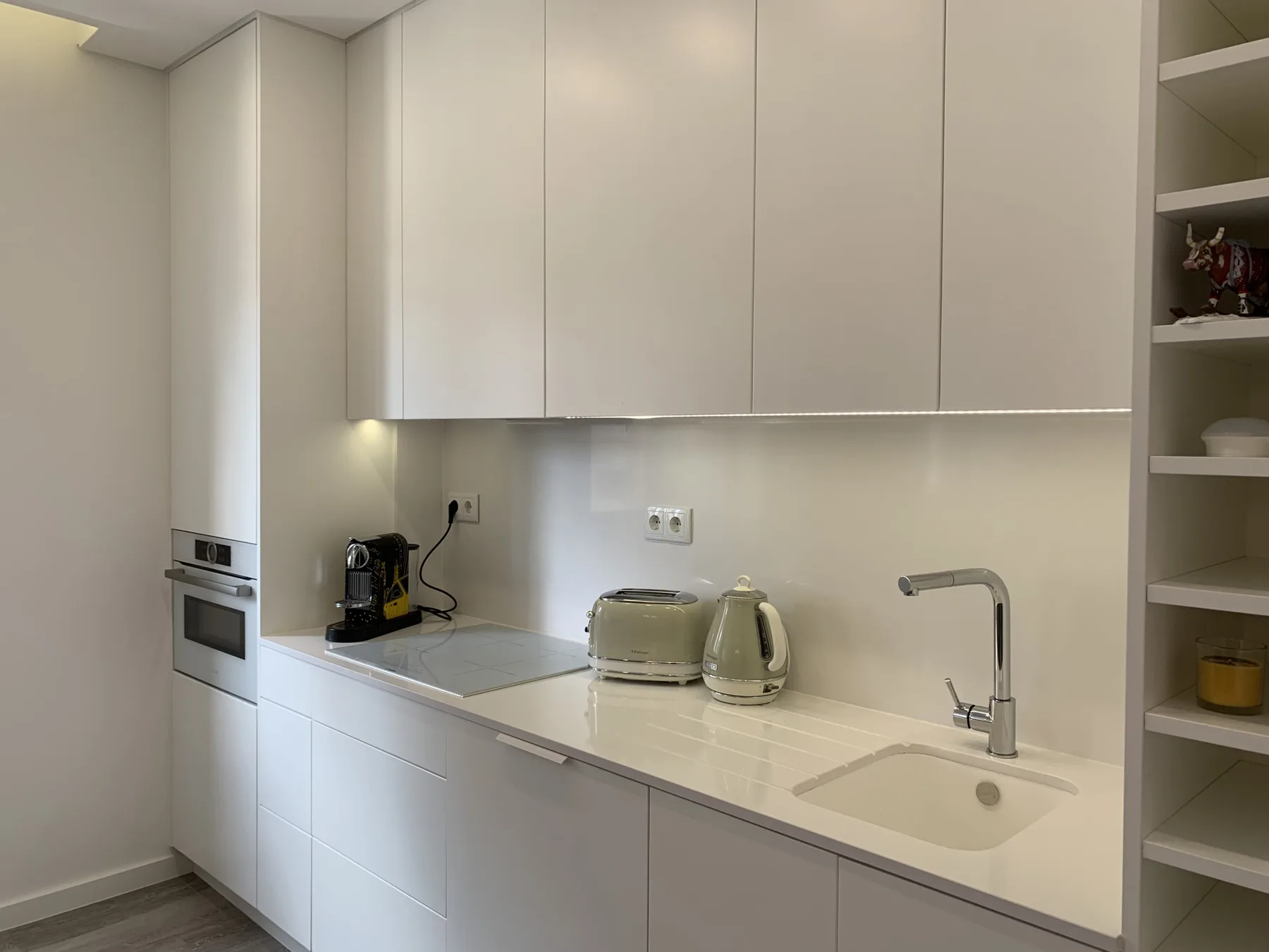 Una cocina moderna con armarios blancos, una encimera y un fregadero.
