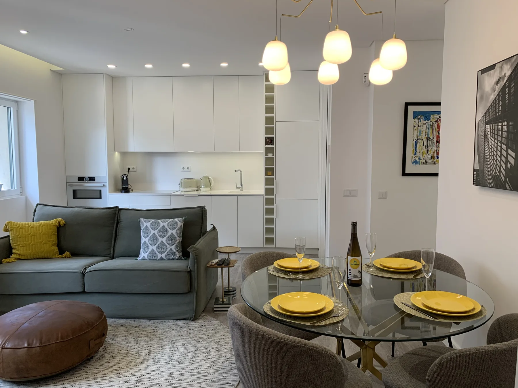 Una sala de estar y comedor con asientos grises y una mesa de comedor de vidrio.