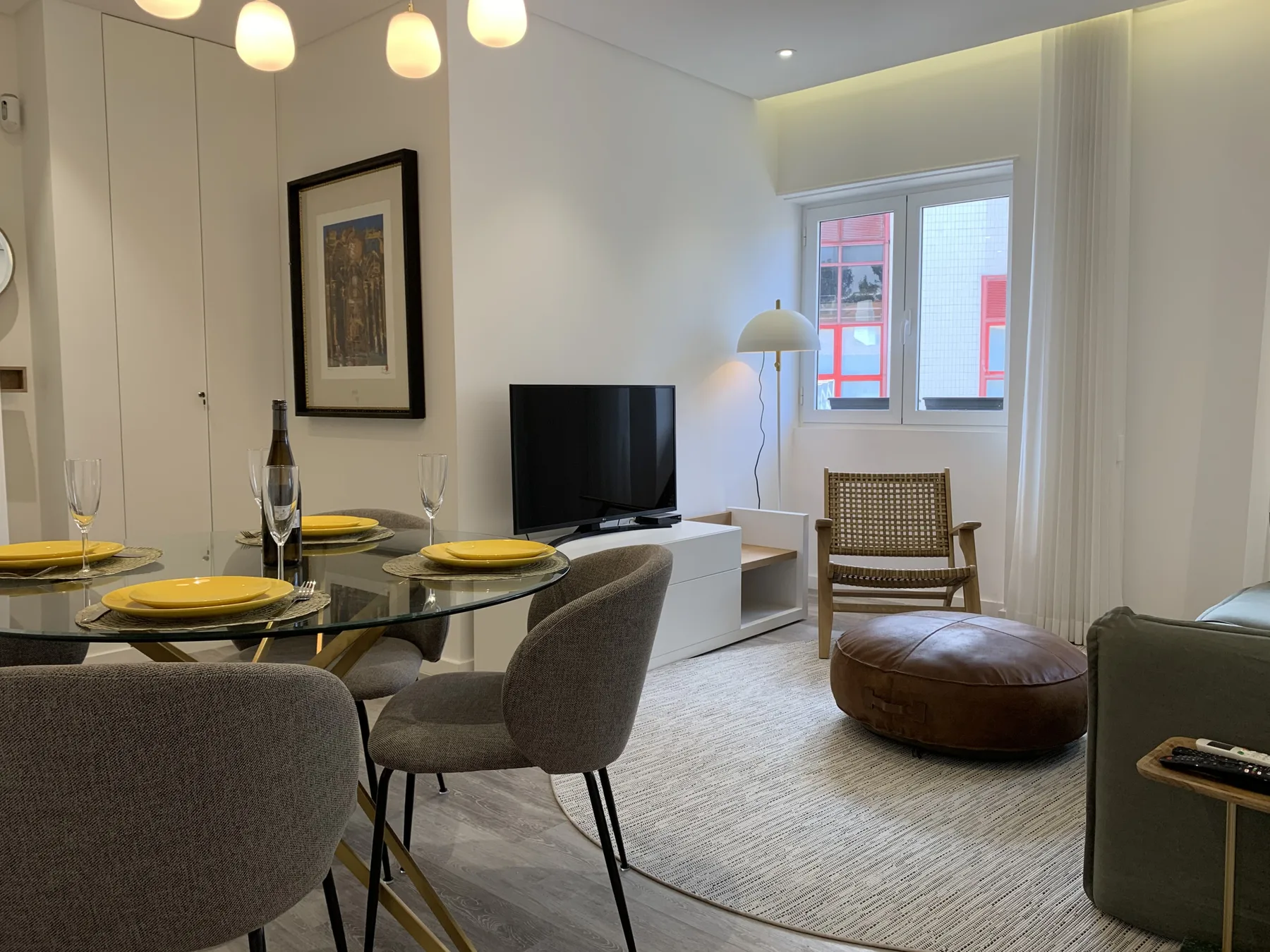Sala de estar y comedor con televisión, mesa de comedor y asientos junto a la ventana.