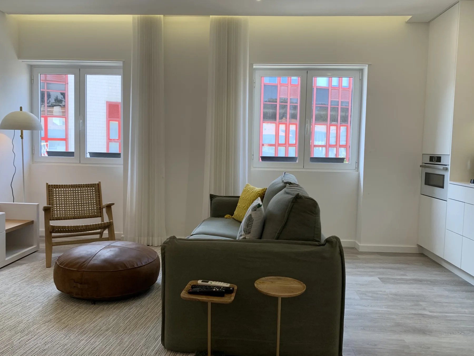 Una sala de estar con asientos, una silla tejida y ventanas.