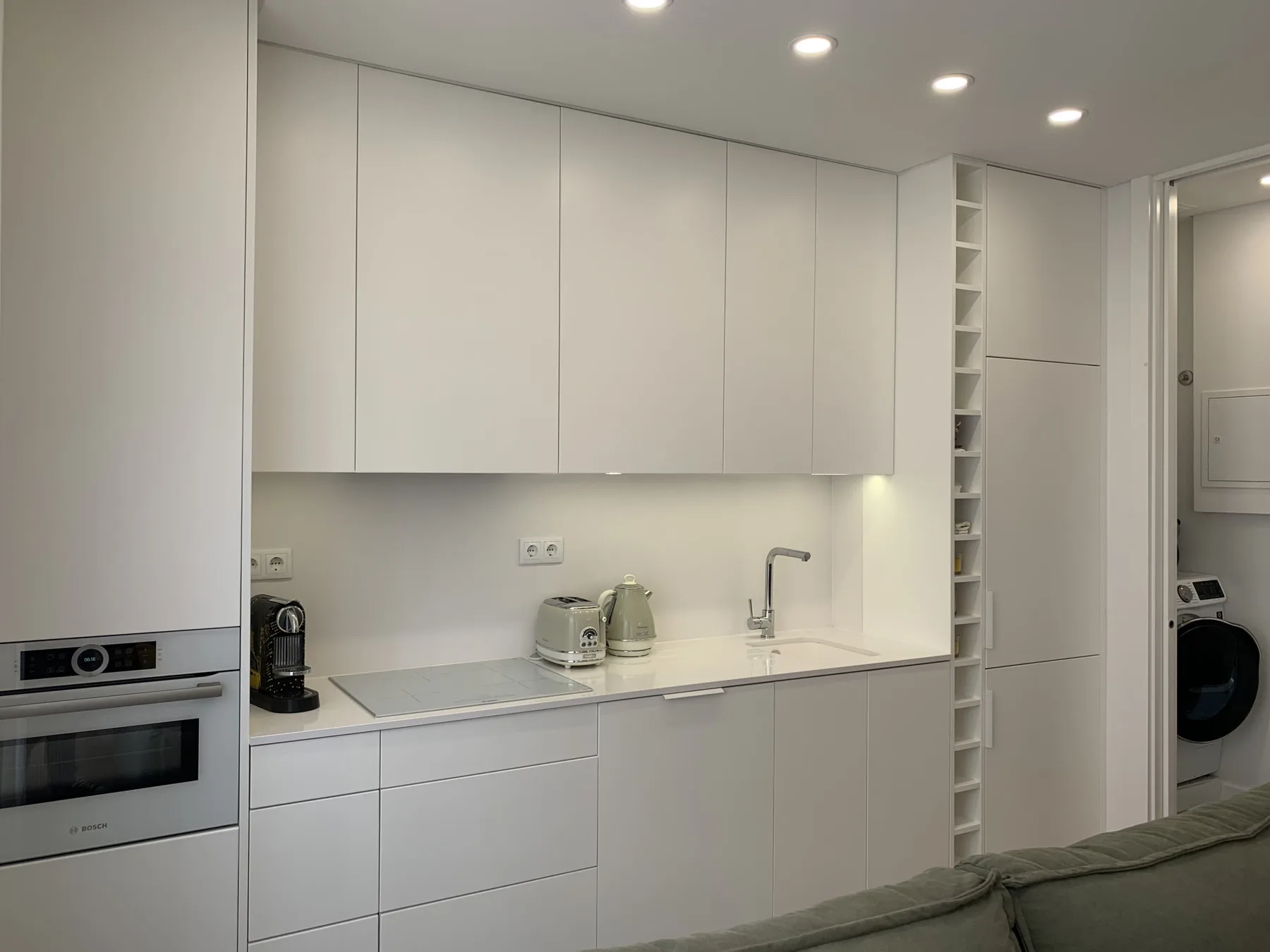 Una cocina blanca y luminosa con electrodomésticos integrados y una encimera.