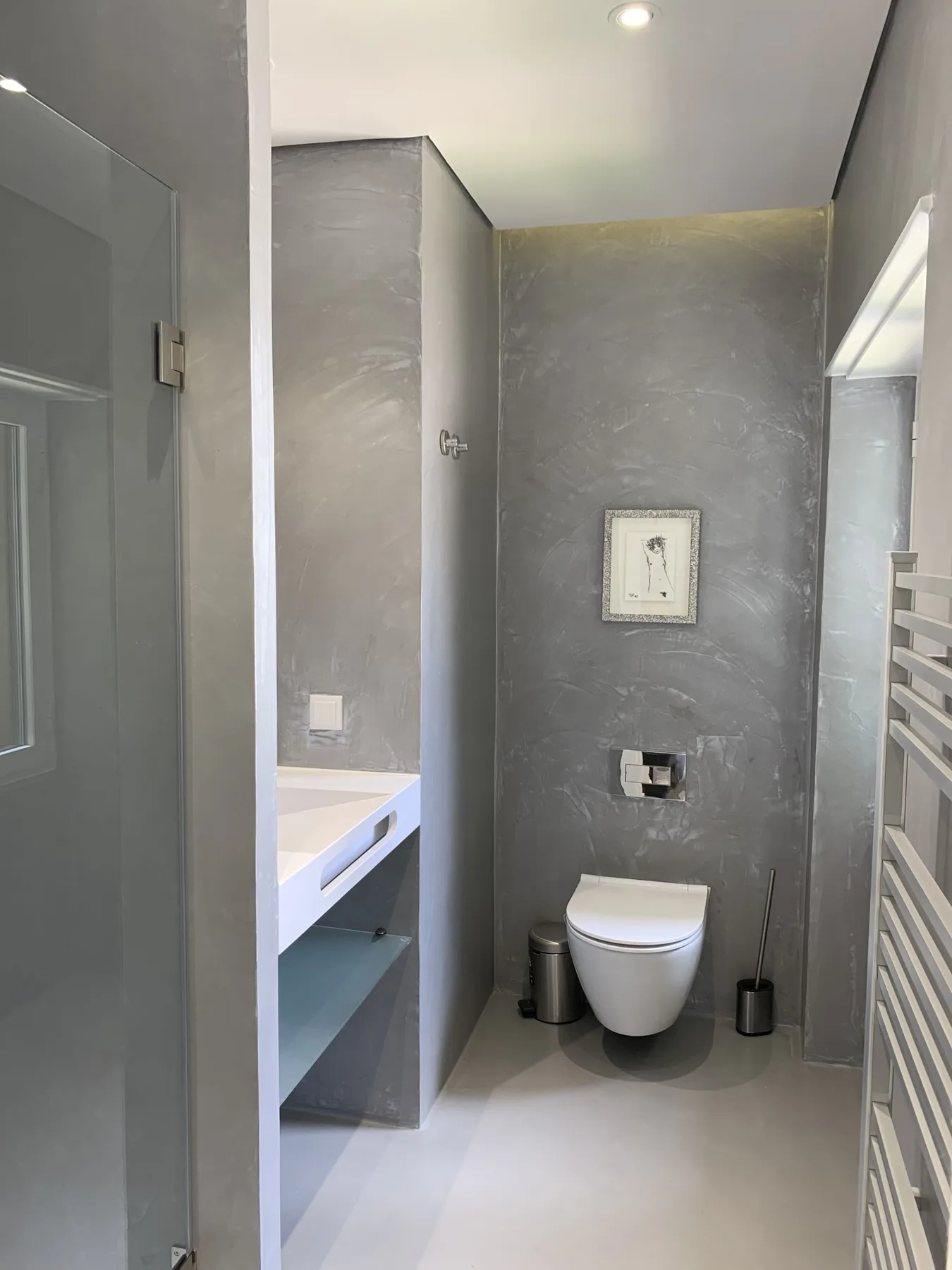 Un baño moderno con un inodoro suspendido y un lavabo.