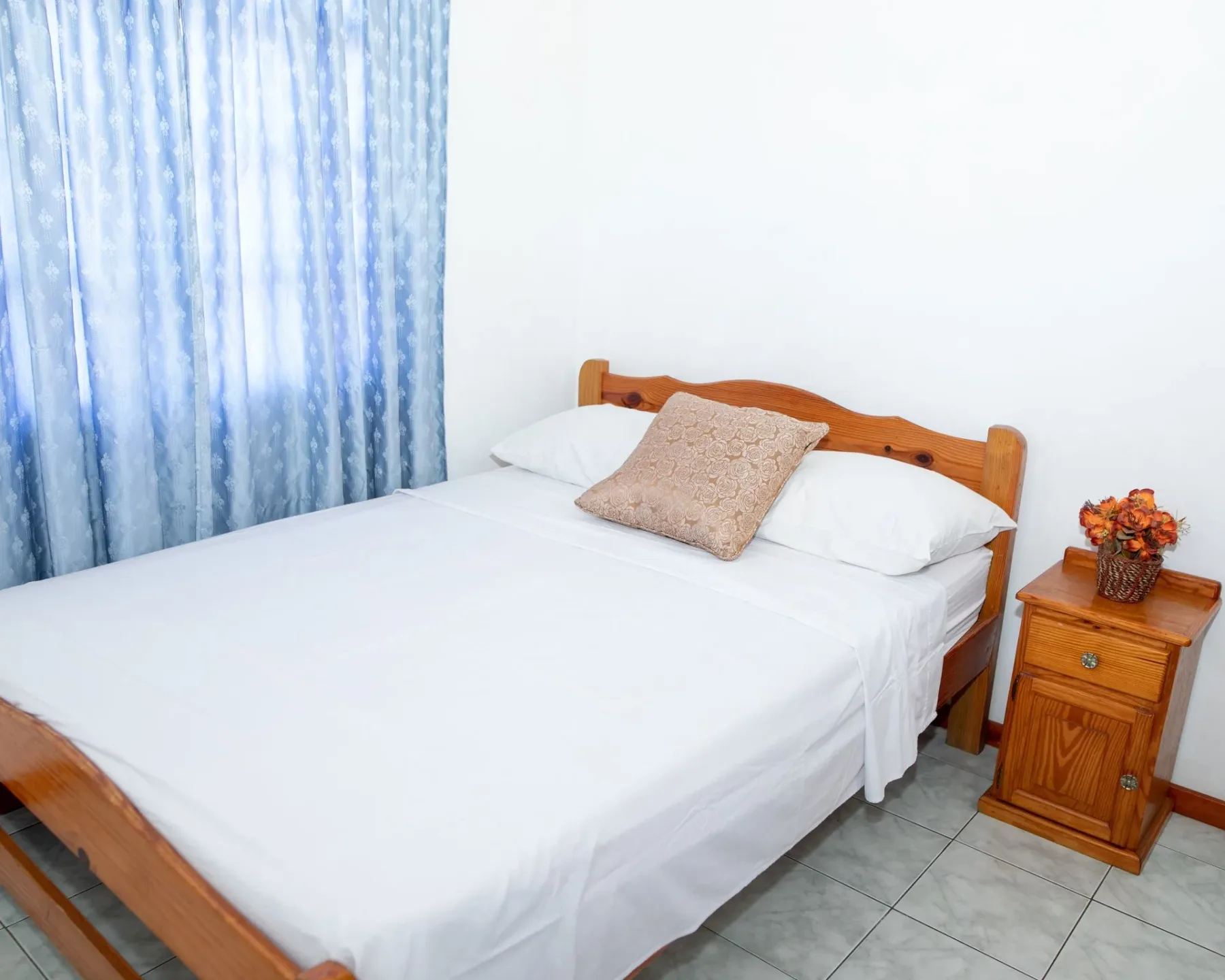 Bedroom with a wooden bed, blue curtains, and a nightstand.