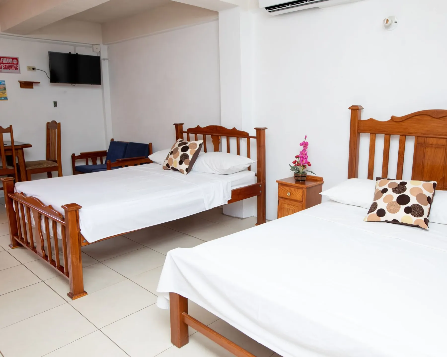 Bright bedroom with two wooden beds and a bedside table.