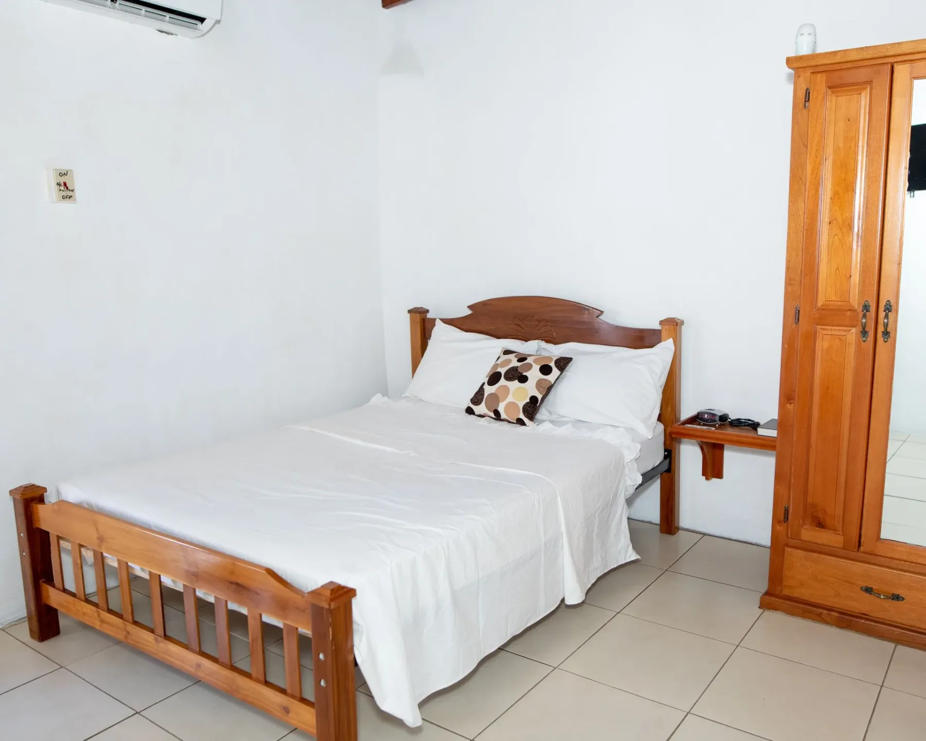Dormitorio con una cama de madera, ropa de cama blanca y un armario.