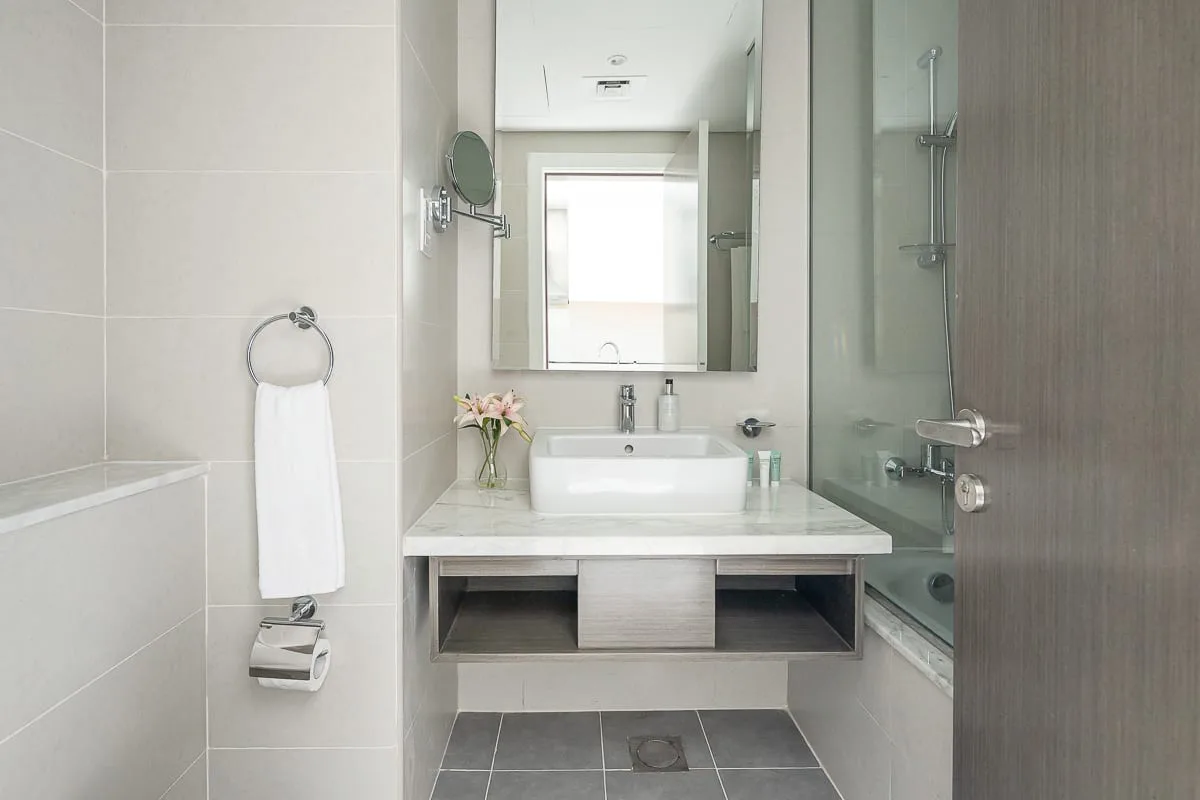 Un baño luminoso con lavabo, espejo y ducha de vidrio.