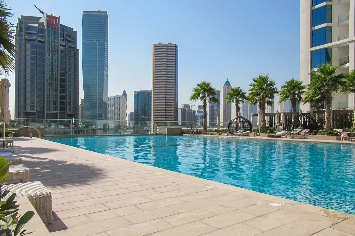 Una piscina en la azotea mira hacia el horizonte de la ciudad, con palmeras junto a la terraza.