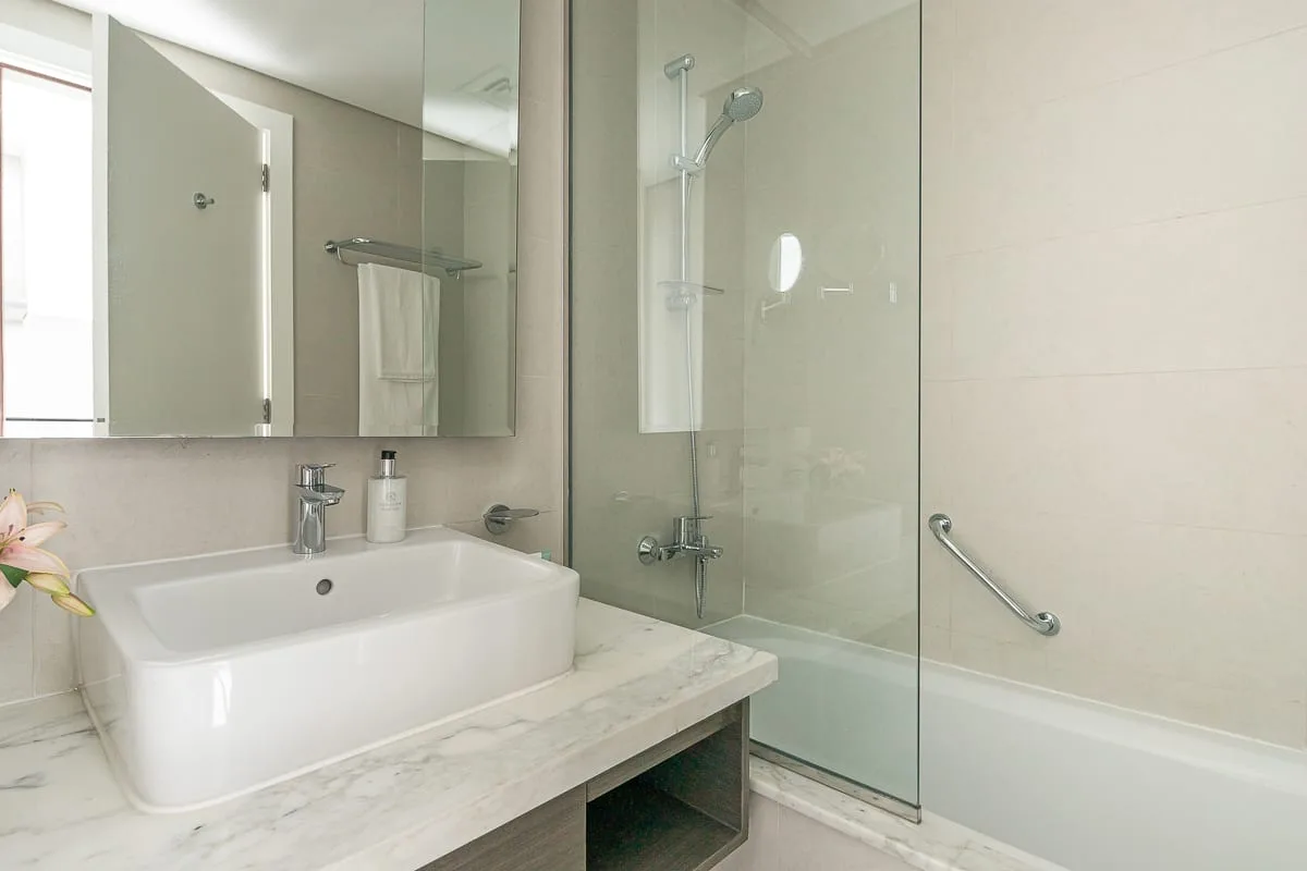 Un baño con lavabo, espejo y ducha de cristal.