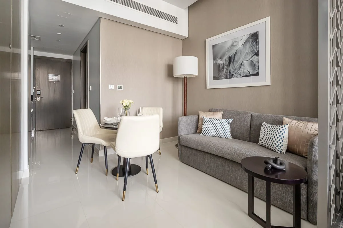 Una sala de estar moderna con un sofá gris, una mesa de comedor y una lámpara de pie.