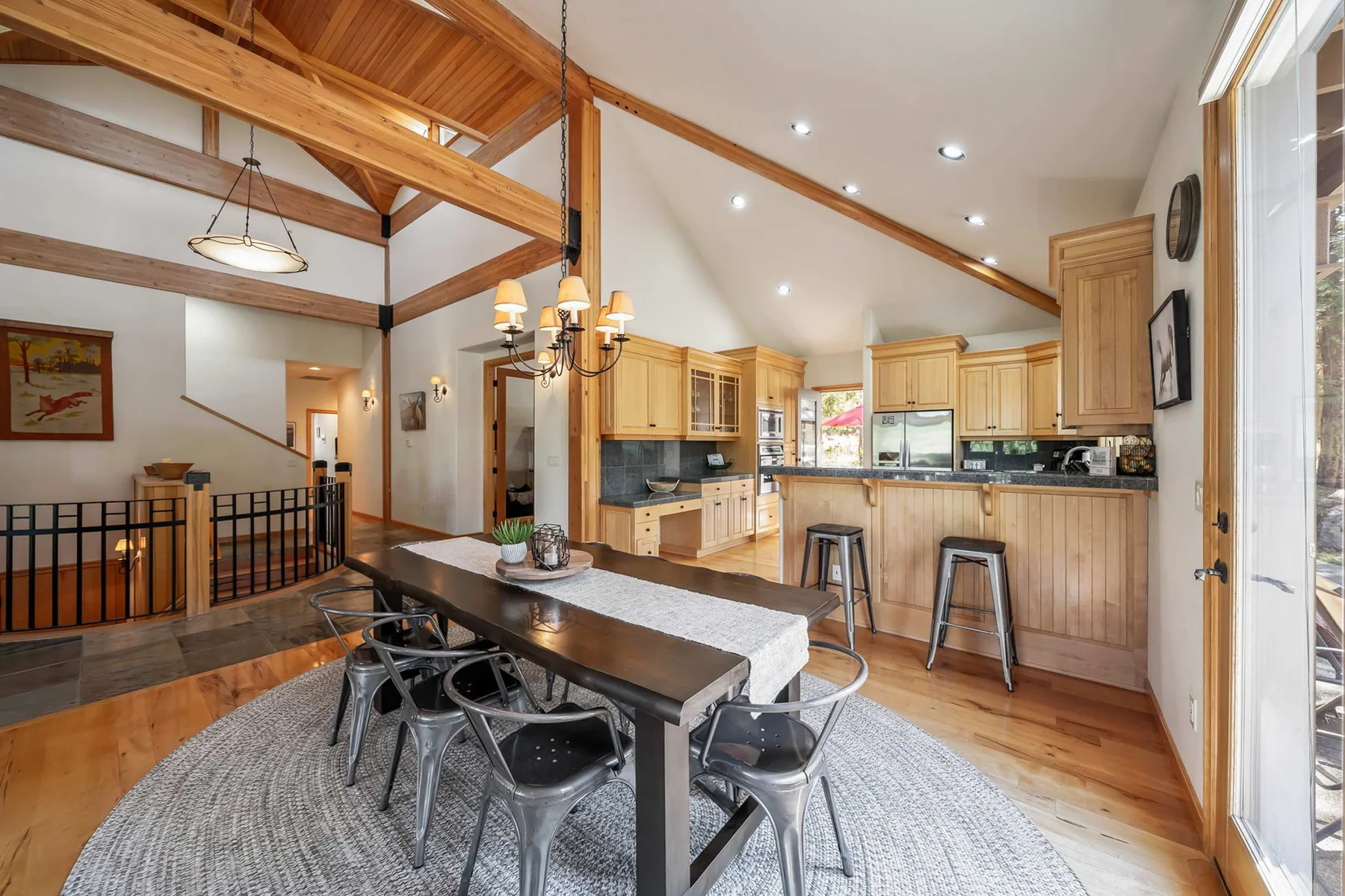 A dining area with a long table beside an open kitchen.