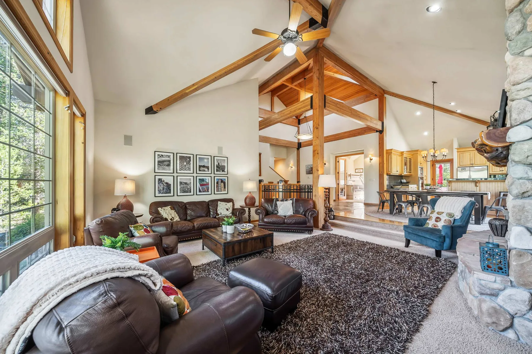 A spacious living room with seating beneath an exposed timber ceiling, open to a dining area.