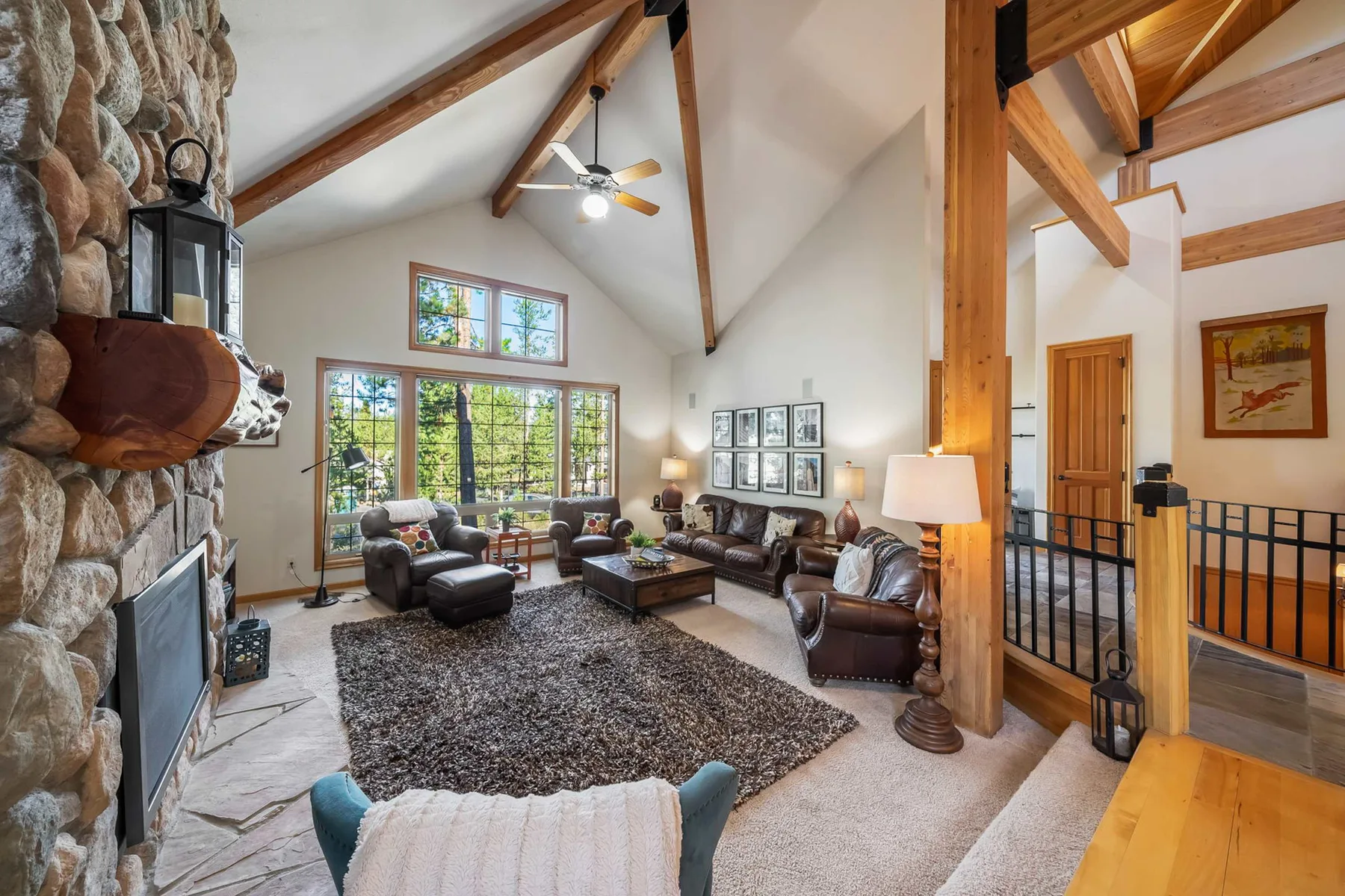 A bright living room with seating around a coffee table and a stone fireplace.