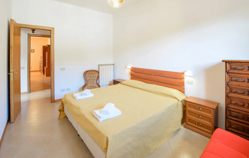 Un dormitorio con una cama doble, mesitas de noche y una silla.