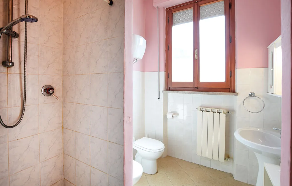 Un baño con ducha, inodoro, lavabo y ventana.