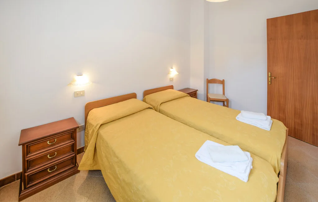 Un dormitorio con dos camas cubiertas con ropa de cama amarilla y una mesita de noche de madera.