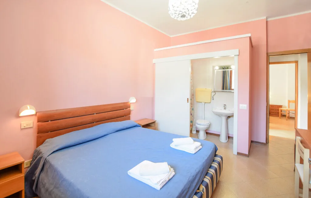 Un dormitorio con una cama azul y un baño contiguo.