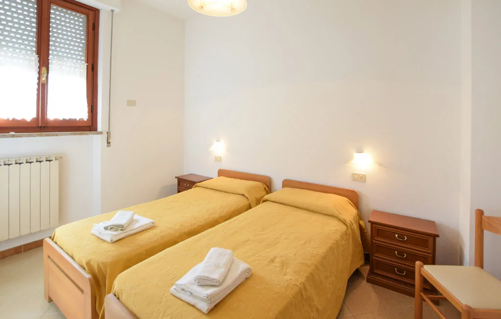 Dormitorio con dos camas, mesitas de noche y una ventana.