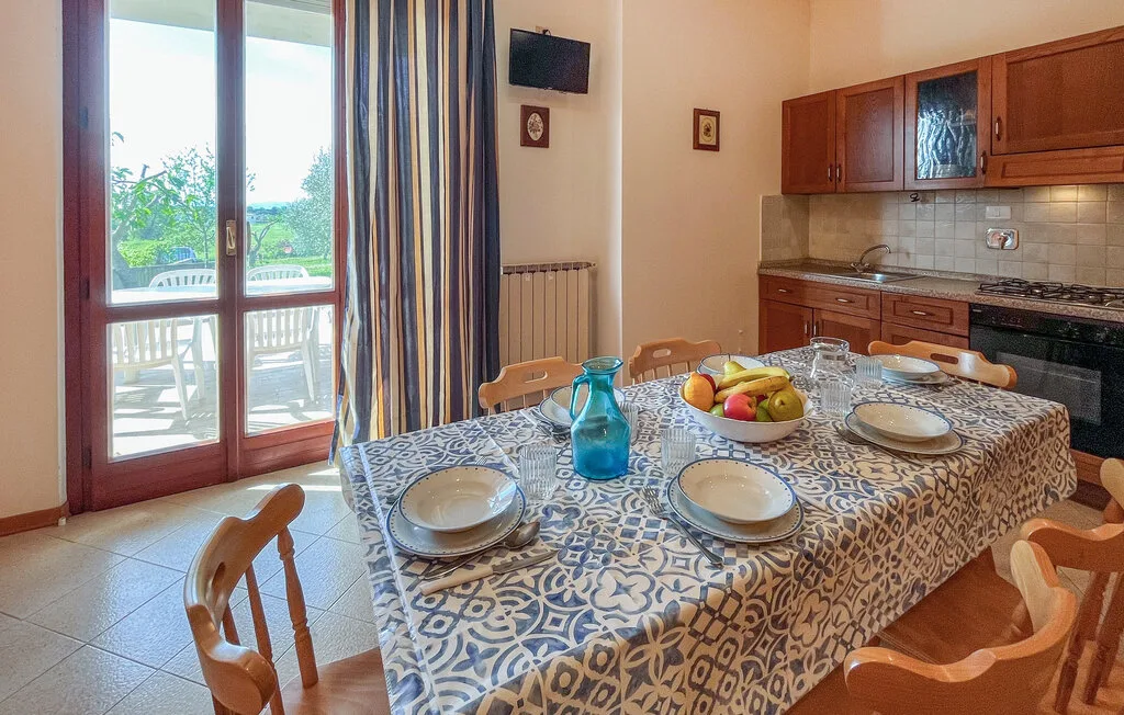 Una mesa de comedor con platos está junto a una cocina y puertas acristaladas.