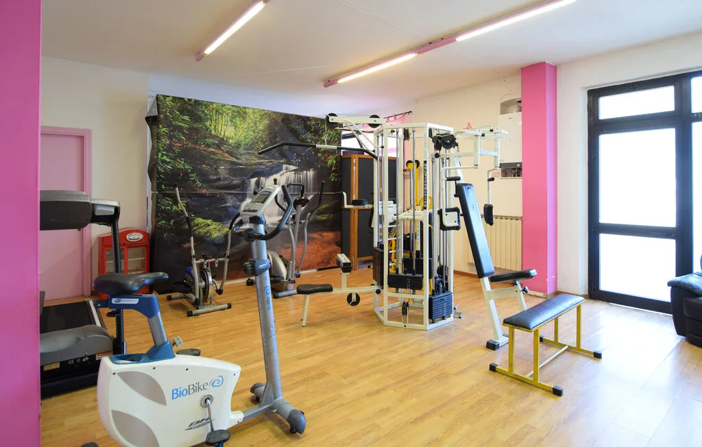 Una sala de ejercicio contiene máquinas de entrenamiento y un banco acolchado.