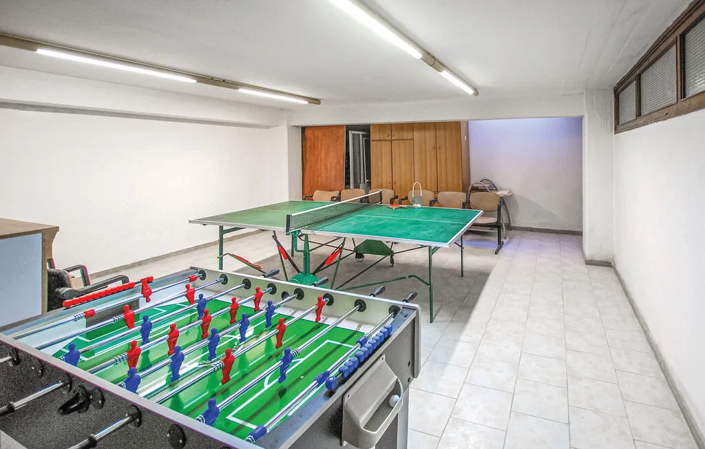 Una sala de juegos con futbolín y una mesa de ping-pong verde.
